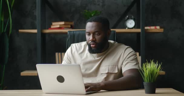 Empresário africano animado vencedor com laptop no local de trabalho. Empreendedor homem feliz gesticulando sim gesto olhando para laptop em emoção depois de ganhar loteria enquanto sentado na mesa no escritório em casa — Vídeo de Stock