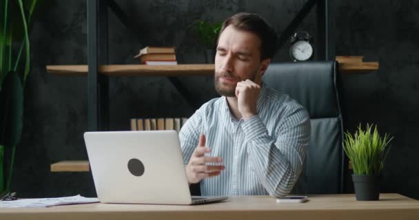 Unpleasantly surprised and shocked businessman by the bad news seen on the laptop screen while working at office. Young male upset with a bad deal, reaction on crisis. — Wideo stockowe