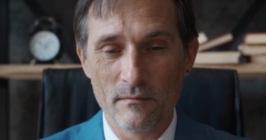 Olgun, profesyonel CEO iş adamı portresi. Kameraya bakıyor ve gülümsüyor. Kendine güvenen yetişkin girişimci, lider, yönetici ofiste oturuyor.