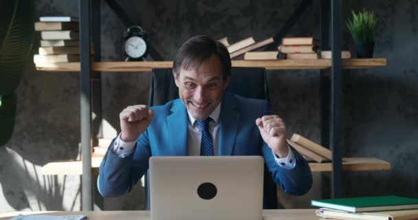 Excited mature businessman winner with laptop at workplace. Happy man entrepreneur gesticulating yes gesture looking at laptop in excitement after winning lottery while sitting at desk at office — Stock Video