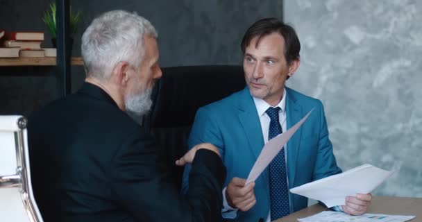 Mature male colleagues discuss business sitting at the table in the office. Executive analysts discussing business diagrams, corporate graphs consulting at office meeting. — Stock videók