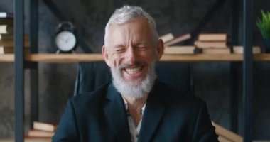 Gülümseyen sakallı, olgun, profesyonel CEO iş adamı kameraya bakıyor. Ofiste poz veren mutlu, yakışıklı, zeki, yetişkin girişimci, lider ve müdürün yakın plan portresi.