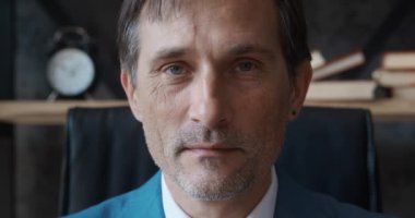 Kameraya bakan ciddi, olgun, profesyonel CEO iş adamı portresi. Kendine güvenen yetişkin girişimci, lider, yönetici ofiste oturuyor.