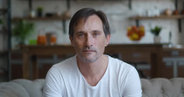 Close-up portrait of successful caucasian mature man smiling looking at camera while sitting at home on sofa. Headshot of senior male on kitchen background — Vídeo de Stock