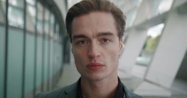 Yakından kendine güvenen şık takım elbiseli bir adam kameraya bakıyor. Yakışıklı iş adamı şehrin dışında duruyor..