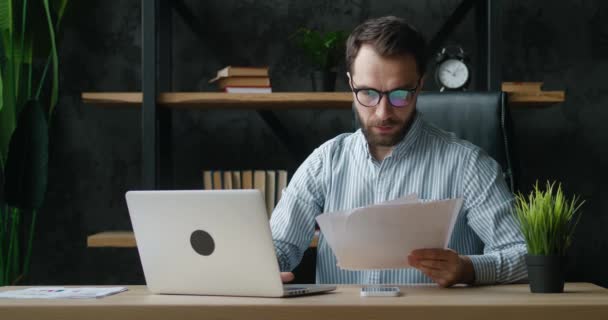 Retrato de un hombre de negocios tiene estrés mientras trabaja en la computadora. El empresario dispersa papeles de negocios y comienza a meditar. Concepto de recuperación de la salud mental — Vídeo de stock