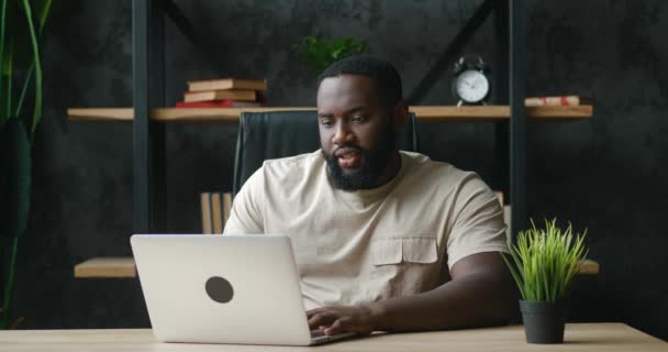 Hombre africano freelancer que trabaja en el ordenador portátil en el lugar de trabajo moderno, remotamente en casa. Empresario masculino que utiliza la computadora, charlando en la red social, escribiendo el mensaje, navegación web del Internet. — Vídeo de stock