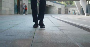 İşe gidip gelen bir iş adamının önü. Kendine güvenen deri ayakkabılı ve resmi takım elbiseli bir adam şehir merkezinde ofis binasının yanında yürüyor..