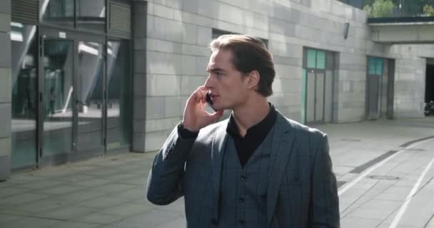 Young business man in formal suit talking phone while walking at downtown in business district. Smiling male entrepreneur talking on mobile phone while going to work — Stock videók