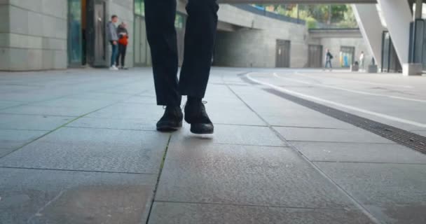 İşe gidip gelen bir iş adamının önü. Kendine güvenen deri ayakkabılı ve resmi takım elbiseli bir adam şehir merkezinde ofis binasının yanında yürüyor.. — Stok video
