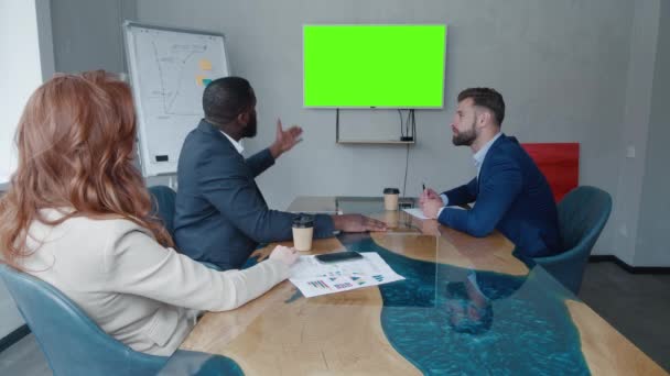 Diverse medewerkers van het bedrijf hebben online business conference video call of videoconferentie presentatie op tv scherm monitor met groene scherm chroma sleutel in de vergaderzaal. — Stockvideo