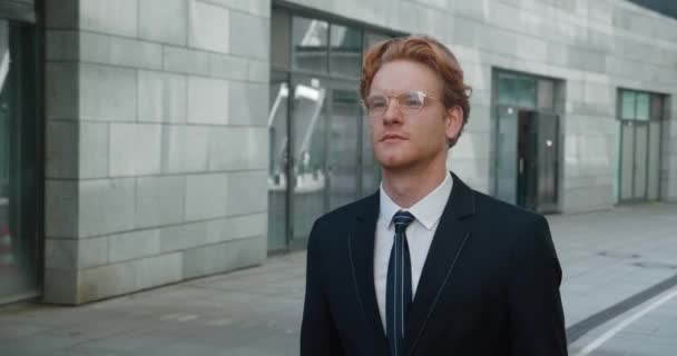 Confident businessman looking away in stylish suit at street. Handsome redhead man walking outside at city. — Stockvideo