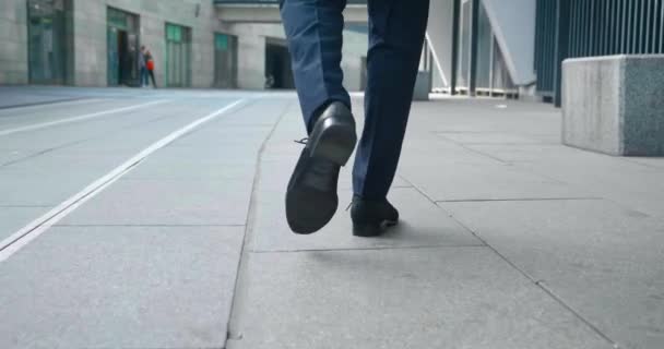 Deri ayakkabılı, resmi takım elbiseli, kendine güvenen bir adamın şehir merkezinde ofis binasının yakınında yürüyüşü. İş adamının dikiz manzarası işe yarıyor.. — Stok video