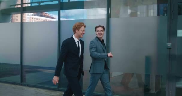 Two men top managers workers discussing business plans walking outdoors along office building. Businessmen in formal suits communicating to each other while going to work — Video
