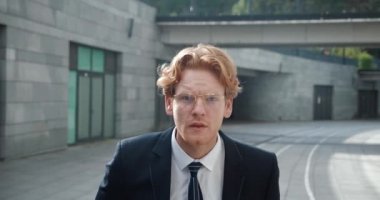 Şok olmuş iş adamı şaşkınlıkla gözlüklerini çıkarıyor. Hayretler içindeki adam kötü haberlerden korkan iş dünyasının arka planındaki kameraya bakar.