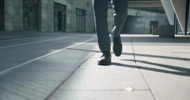 Siyah ayakkabılı iş adamlarının ayakları ve resmi kıyafetleri ön planda, dışarıda yürüyor, adımlar atıyor, işe gidip geliyor, düzenli çekim yapıyor..