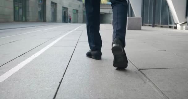 Back view of confident man in leather shoes and formal suit start walking down the street of the business district. Rear view feet of serious businessman going to work. — Video Stock