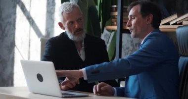 Masada otururken modern ofiste iş büyümesini tartışan iki yetişkin iş adamı. İçerde buluşurken iş arkadaşınla anlaşma hakkında konuşan bir adam.