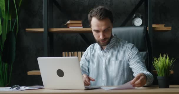 現代のオフィスに座っている間、ビデオ会議でオンラインで話しているハンサムなビジネスマン。ウェブカメラのラップトップコンピュータを屋内で見るプロジェクトを説明するビデオ通話を持つ従業員. — ストック動画