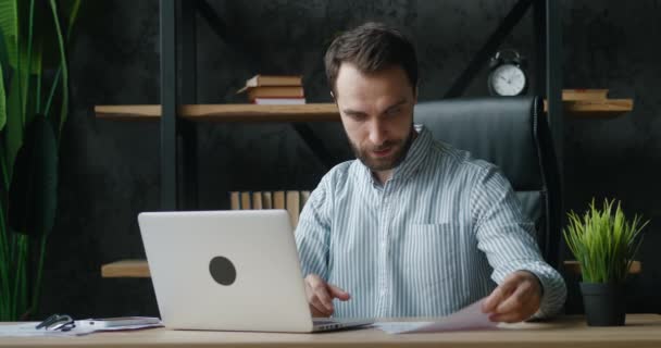 Hombre de negocios guapo hablando en videoconferencia en línea mientras está sentado en la oficina moderna. Empleado teniendo videollamada explicando proyecto mirando webcam ordenador portátil interior. — Vídeo de stock