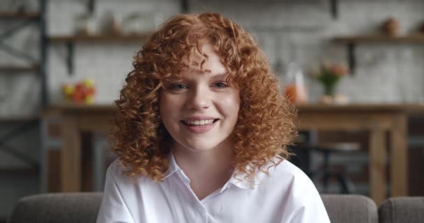 Geschokt jonge roodharige vrouw met krullend haar die ja gebaar toont terwijl ze thuis zit. Jonge vrouw vieren succes te winnen overwinning. Loterij win concept. — Stockvideo