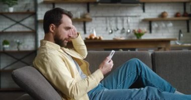 Şok olmuş bir adam evinde elinde akıllı telefonuyla koltukta dinleniyor. Olumsuz mesajlar okuyor, rahatsız oluyor, cihaz sorunu yaşıyor. Ne yazık ki, erkek kötü SMS, cihaz sorunu, uygulama çökmesi konsepti almış.