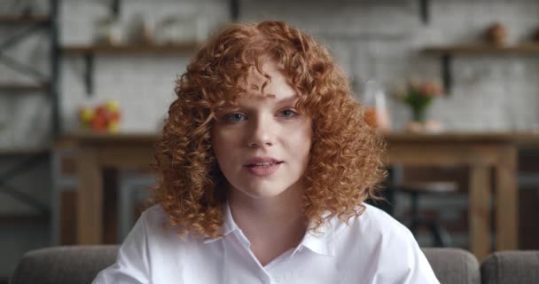 Oh my god wow. Amazed redhead woman with curly hair looking at camera. Pleasantly surprised young student female on the background of the home interior apartment — Stock Video