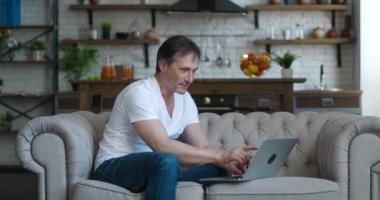 Dizüstü bilgisayara bakan heyecanlı olgun adam başarıyı kutluyor online bahsi kazanıyor ve EVET hareketi gösteriyor. Şanslı son sınıf öğrencisi internette harika haberler okuyor. Evdeki rahat koltukta dinlenirken bilgisayar kullanıyor..