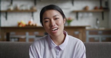 Sohbet üzerine konuşan Asyalı genç bir kadın çevrimiçi sohbetin tadını çıkarıyor. Kameraya bakıyor, gülümseyen kadın blogcu etkileyicisi video bloguna konuşuyor. Web kamerası görünümü.