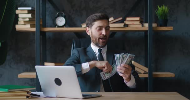 一个身披正式西装的大胡子的成功商人把钞票扔在现代办公室的桌子前玩乐，独自享受着财富。富人、生活方式和商业概念. — 图库视频影像