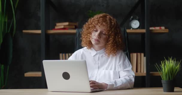 Stressed young woman business woman suffering from overwork headache from working at the computer while sitting at the table in the office. Bored red-haired student tired of working at a laptop — Stock Video