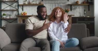 Mutlu, genç, ırklar arası bir çift evde evliliklerini duyurmak için video görüşmesi yapıyor. Gülümseyen genç adam ve kadın kameraya el sallıyor ve konuşuyor, sonra nişan yüzüğü gösteriyor.