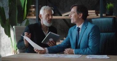 Şirket toplantısında iki olgun iş adamı. Erkek iş ortakları ofis masasında otururken iş projesini tartışırken beyin fırtınası yapıyorlar