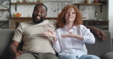 Webcam görüntülü birkaç blogcu kamerayla konuşuyor, internet için video kaydediyor, evdeki kanepede oturuyor. Afrikalı erkek ve Kafkasyalı kadın, oturma odasında video blogu arıyor veya kaydediyor