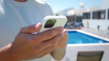 Kapalı parmaklar akıllı telefonun ekranına dokunuyor, güneşli yaz gününde açık havada mobil bir mesaj yazıyor. Erkek eller cep telefonu tutuyor ve şehirdeki e-postaları kontrol ediyor..