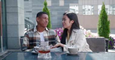 Çekici, mutlu bir çift yaz kafeteryasının terasında dinleniyor, sohbet ediyor, birlikte eğleniyor sıcak güneşli bir günde sıcak çay ikram ederek masada dinleniyor.