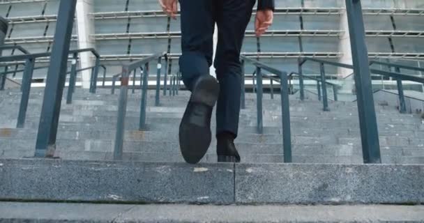 En affärsmans ben i svarta skor som går uppför trappan utanför affärsbyggnaden. Manlig entreprenör i formell kostym går till jobbet — Stockvideo