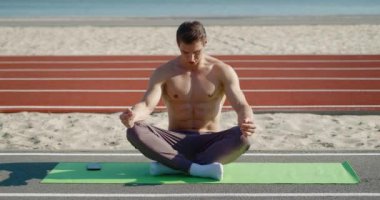 Lotus 'ta oturan genç sporcu dışarıda meditasyon yapıyor. Zen meditasyon pratiği, genç atletik adam dışarıda meditasyon, zen sağlık ve sağlık