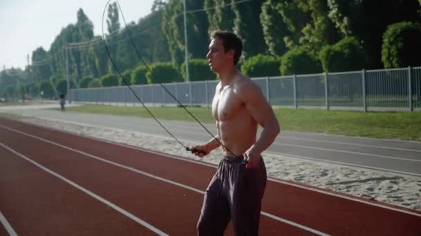 Athletic man jumping rope outdoors. Caucasian handsome male exercising with skipping rope — Stock Video