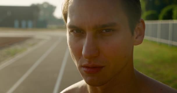 Portrait of handsome strong man. Healthy athletic fitness model posing outdoors at stadium. — Stock Video