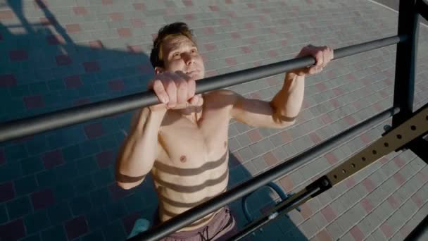 Fiatal atlétikai férfi csinál húzza fel gyakorlatok vízszintes rúd alatt intenzív edzés szabadban. jóképű férfi edzés a városi parkban nyáron — Stock videók