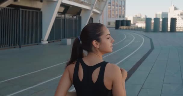 Tylny widok szczęśliwej atletycznej kobiety biegającej na świeżym powietrzu w zwolnionym tempie. Fitness dziewczyna robi trening cardio, działa rano na ulicach miasta — Wideo stockowe