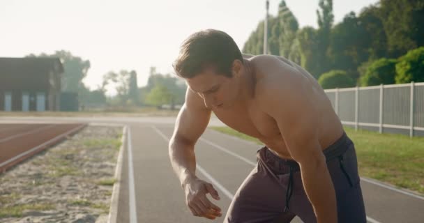 Atletische sportieve man ontspannen na run buiten op het stadion. — Stockvideo