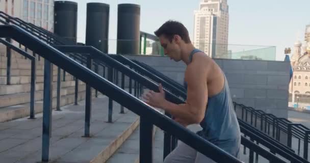 Młody człowiek sportowiec biegnie po schodach szkolenia intensywny trening cardio ćwiczenia biegacz męski jogging na schodach w tle miasta miejskiego — Wideo stockowe