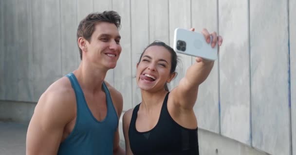 Odpowiednia para sportowa, młody mężczyzna i kobieta biegacze robiący zdjęcia selfie na smartfonie po treningu fitness na świeżym powietrzu — Wideo stockowe