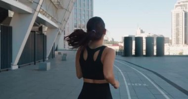 Atletik genç kadın ağır çekimde dışarıda koşuyor. Fitness kızı antrenman yapıyor, sabah şehir sokaklarında koşuyor.