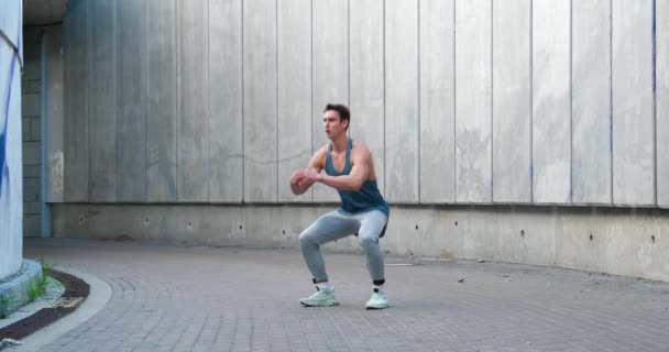 Jovem atlético fazendo exercícios de agachamento, treinamento esportivo sozinho. Exercício ao ar livre. — Vídeo de Stock