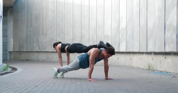 Sports couple train together. Strong athletic man doing push-ups with woman on his back. Fitness workout training outdoors — Stock Video