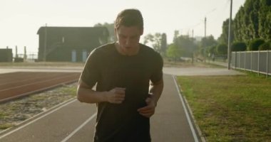 Spor adamı boksörünün dışarı koşması ön planda. Stadyumda koşan adamın portresi. Gün batımında dışarıda spor yapıyorum. Atletik eğitim koşusu egzersizi