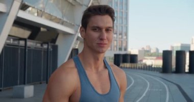 Yakışıklı, güçlü bir gencin portresi. Sağlıklı atletizm modeli kameraya bakıyor ve gülümsüyor, stadyumda ayakta duruyor.. 